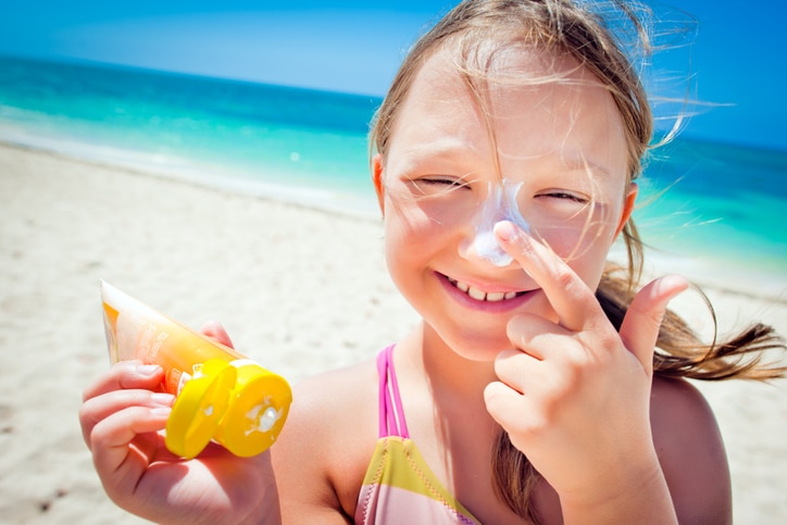 Girl applying sunscreen to her nose