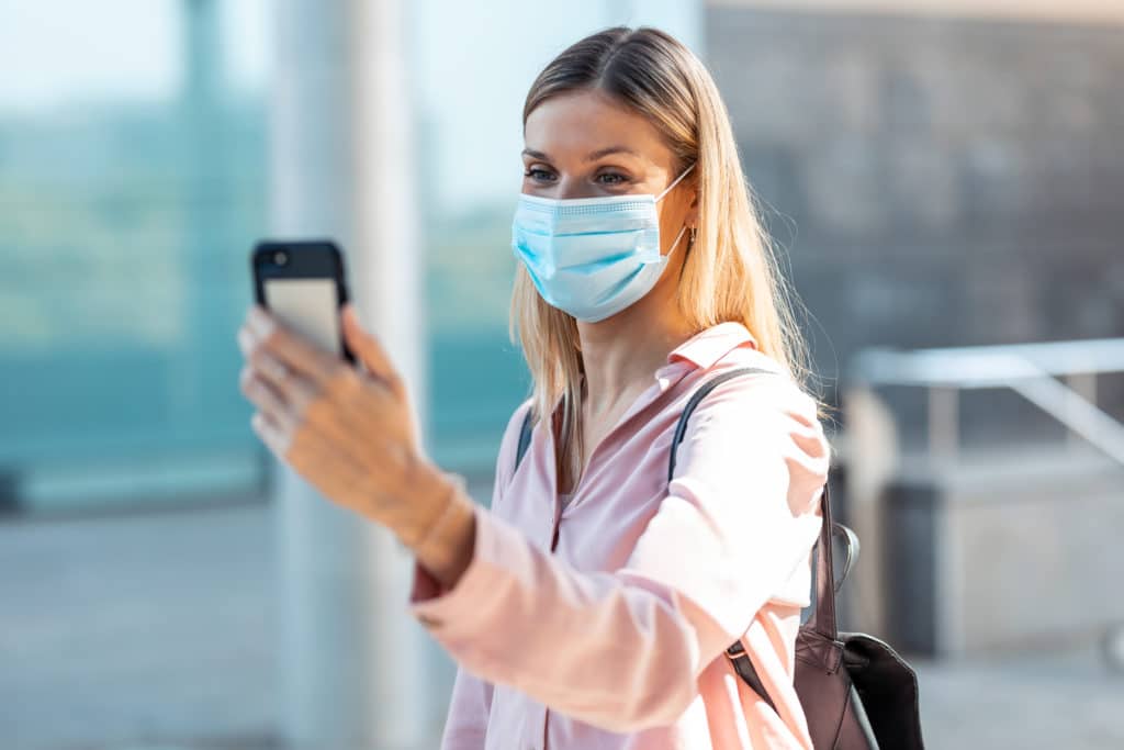 beautiful blonde woman in face mask doing a selfie rqs4q33