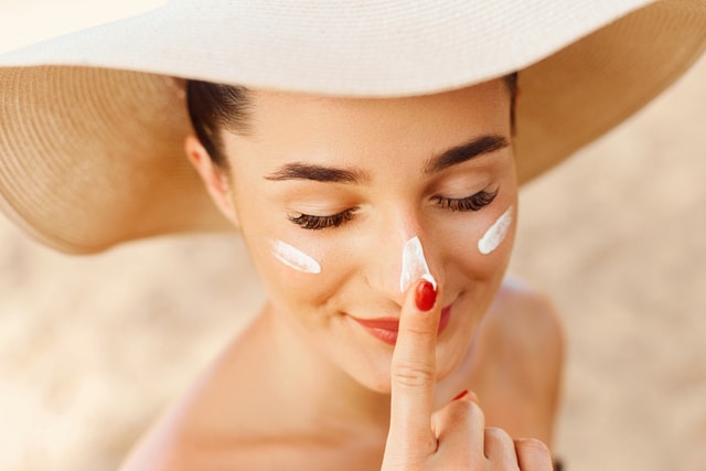 Beautiful Young woman with sun cream on face.