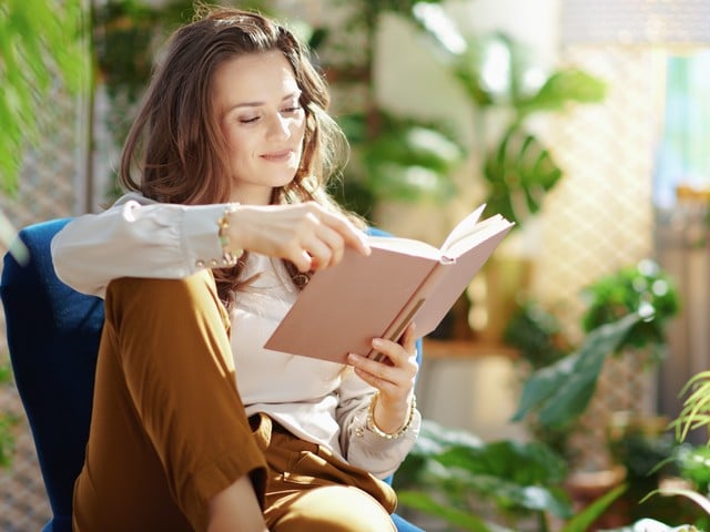 relaxed middle aged woman with long wavy hair reading a book