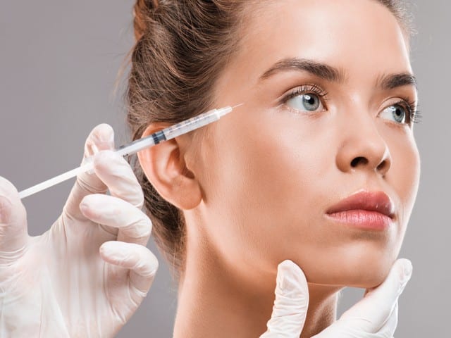 beautiful woman getting botox injection for eyes area
