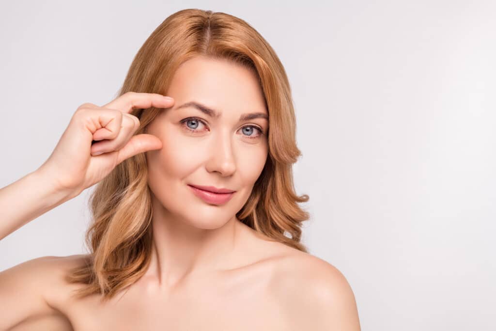A woman pointing to her eyes after getting BOTOX Cosmetic for crow's feet